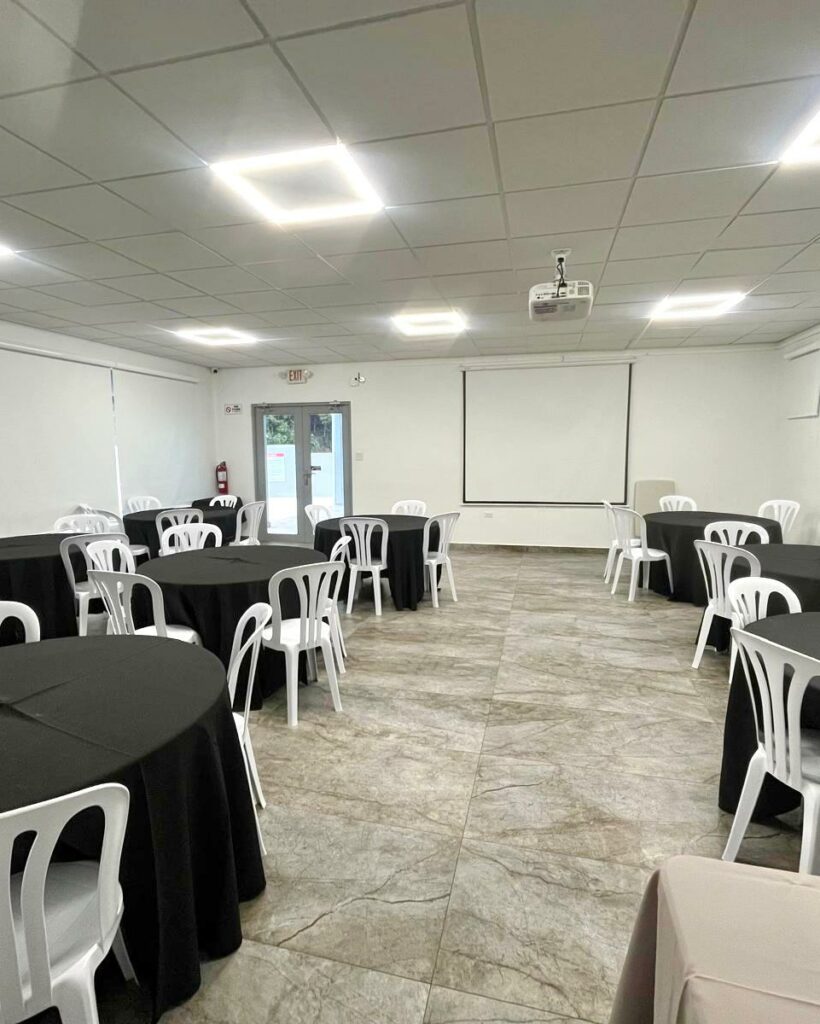 salón con mesas negras y sillas blancas